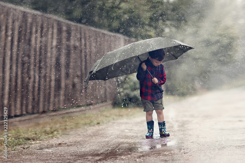 boy standing under umbrella in rain