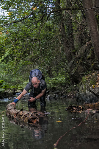 Man pushing wood logs in a riverbed