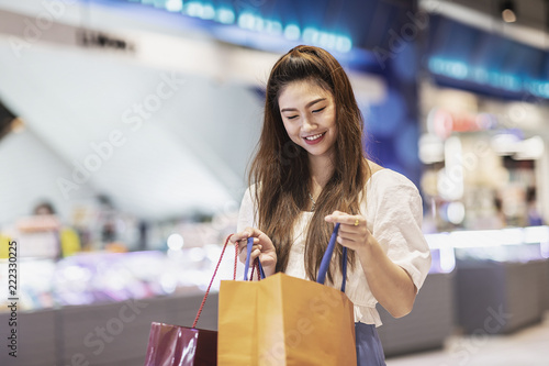 Beautiful Attractive Asian woman open shopping bags after shopping smile and enjoy with it in shopping mall so happiness and cheerful,Shopping Concept