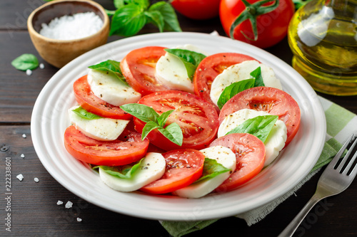 Bilde på lerret Italian caprese salad with tomatoes, mozzarella cheese and basil in plate on dar