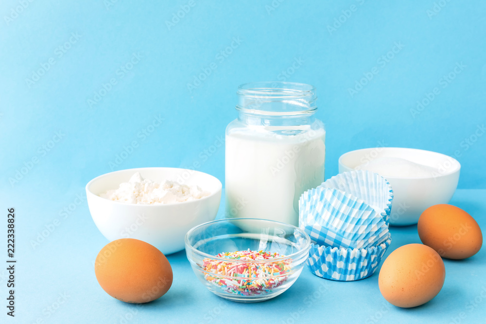 Eggs, flour, milk, sugar, and various ingredients for making pastry homemade pastry on a blue background with copy space Eggs, flour, milk, sugar, and various ingredients for making pastry homemade pastry on a blue background with copy space