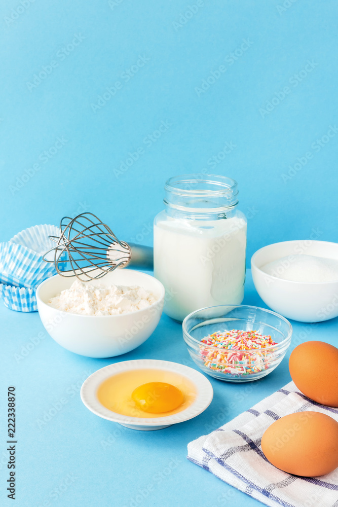 Eggs, flour, milk, sugar, and various ingredients for making pastry homemade pastry on a blue background with copy space Eggs, flour, milk, sugar, and various ingredients for making pastry homemade pastry on a blue background with copy space