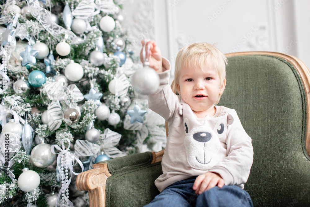 Portrait little boy. Happy new year. decorated Christmas tree. Christmas morning in bright living room. sitting on green chair Portrait little boy. Happy new year. decorated Christmas tree. Christmas morning in bright living room. sitting on green chair