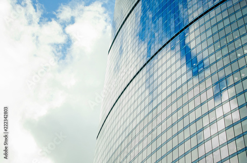 Fragment of a wall of a skyscraper with mirror glass against a sky with clouds. Close-up.