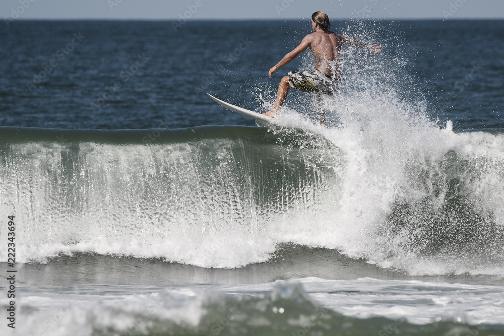 Junger männlicher Surfer in Shorts reitet auf dem Wellenkamm
