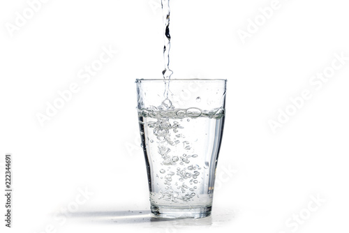 water is poured into a drinking glass, isolated on a white background with copy space