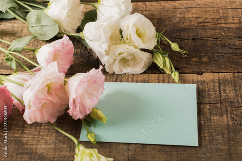 Blooming flowers of lisianthus, eustoma with grittings card on the wooden table.