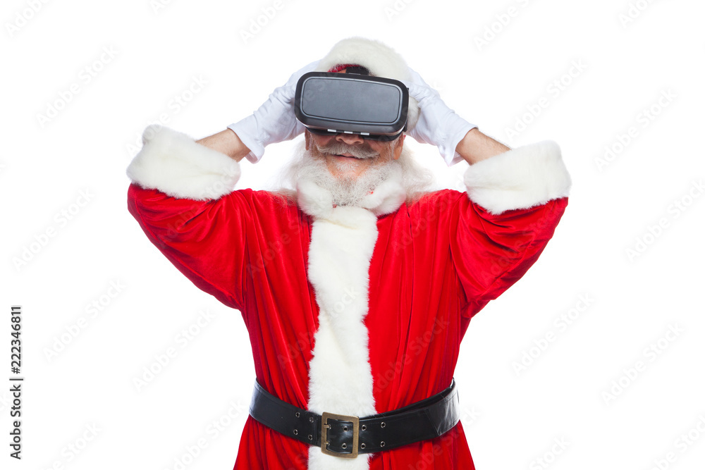 Christmas. Santa Claus in black virtual reality glasses makes gestures with his hands. Surprise, emotion. New technology. Isolated on white background. Christmas. Santa Claus in black virtual reality glasses makes gestures with his hands. Surprise, emotion. New technology. Isolated on white background.