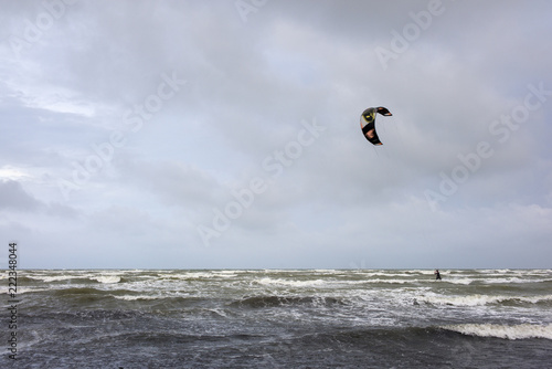 alone kite-surfer in stormy sea under dramatic clouds