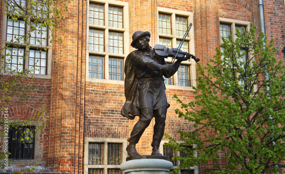 Naklejka premium Fountain sculpture of musician in old town of the city, sunny day, Torun, Poland