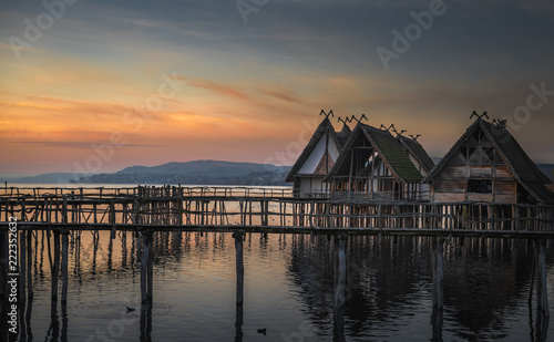 Antique wooden huts on water at sunset