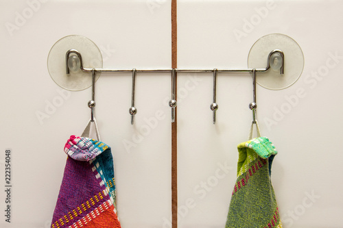 Tableau sur toile Two colourful towels hanging on a hooks with suction cups in a kitchen