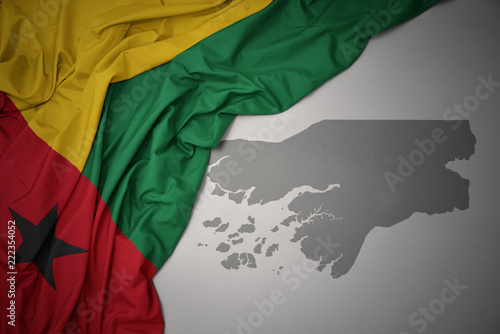 waving colorful national flag and map of guinea bissau.
