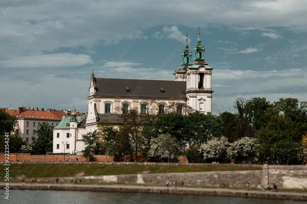The river flows through the city. Church on the hill above the river. Wisla River in Krakow. Float the boat and the ship under water The river flows through the city. Church on the hill above the river. Wisla River in Krakow. Float the boat and the ship under water