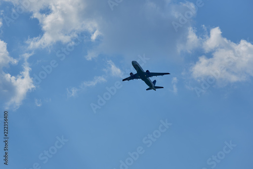 Passenger airplane flying against white clouds and blue sky.