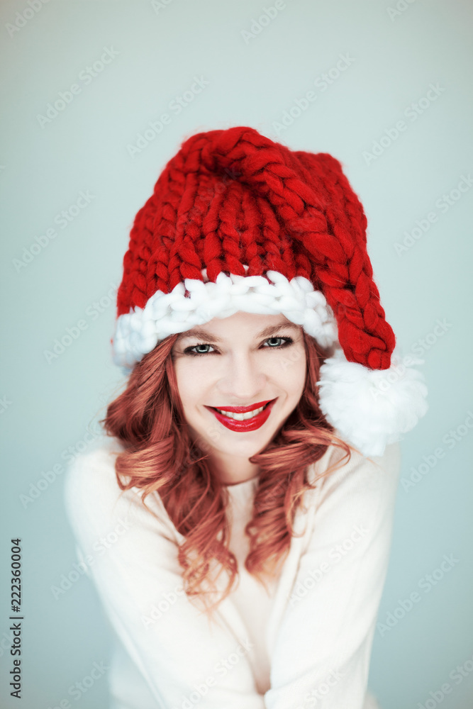 Santas little helper. Beautiful happy young woman with a santa claus hat, perfect make up, red lipstick, can be used as background Santas little helper. Beautiful happy young woman with a santa claus hat, perfect make up, red lipstick, can be used as background