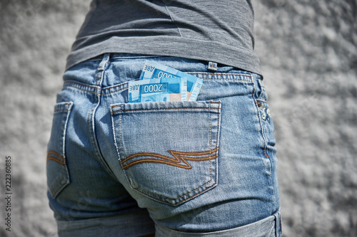 money in the back pocket of jeans girls on a gray background
