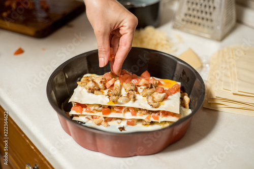 Woman preparing meat lasagna. meat, tomatoes and cheese lay with his hand