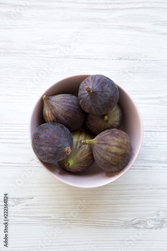 Fresh figs in a pink bowl on a white wooden background. Top view, overhead, from above. Close-up.
