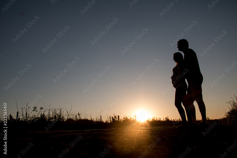 Young couple expects the first son looking into his eyes at sunset.