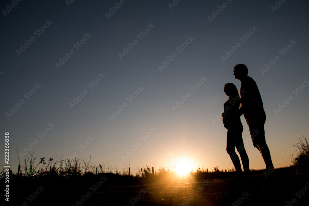 Young couple expects the first son looking into his eyes at sunset.