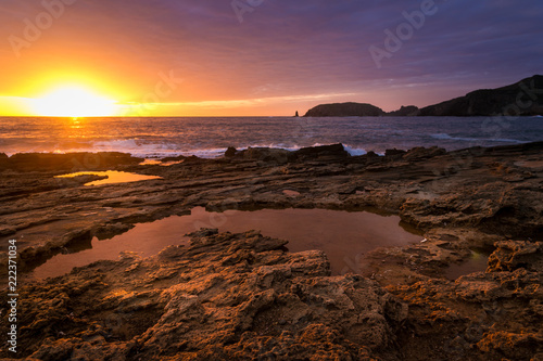 Wonderful sunset while cloudy sky reflects on sea water puddle