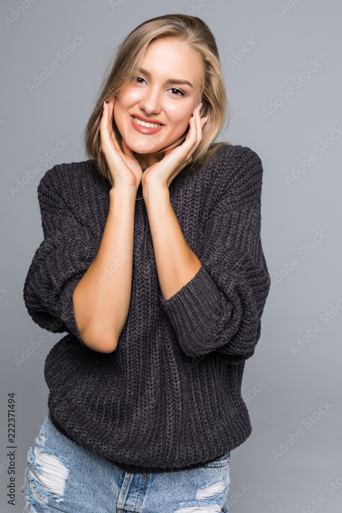 Young woman with a thoughtful friendly smile looking sideways at the camera and copy space isolated on gray background Young woman with a thoughtful friendly smile looking sideways at the camera and copy space isolated on gray background