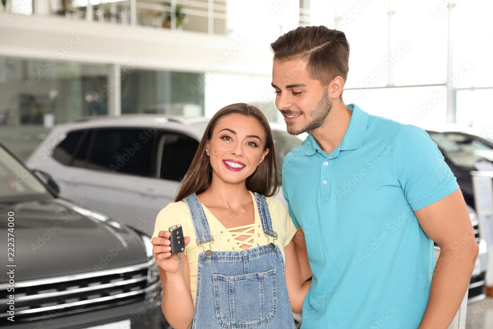 Happy couple with car key in salon Happy couple with car key in salon