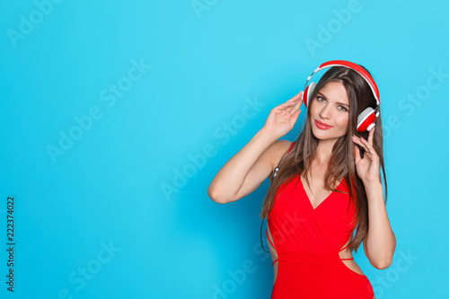 Sexy young woman in bikini listening to music on color background