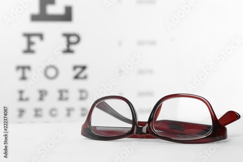 Glasses with corrective lenses on table against eye chart
