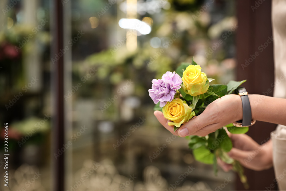 Fototapeta premium Female florist holding beautiful bouquet in flower shop, closeup