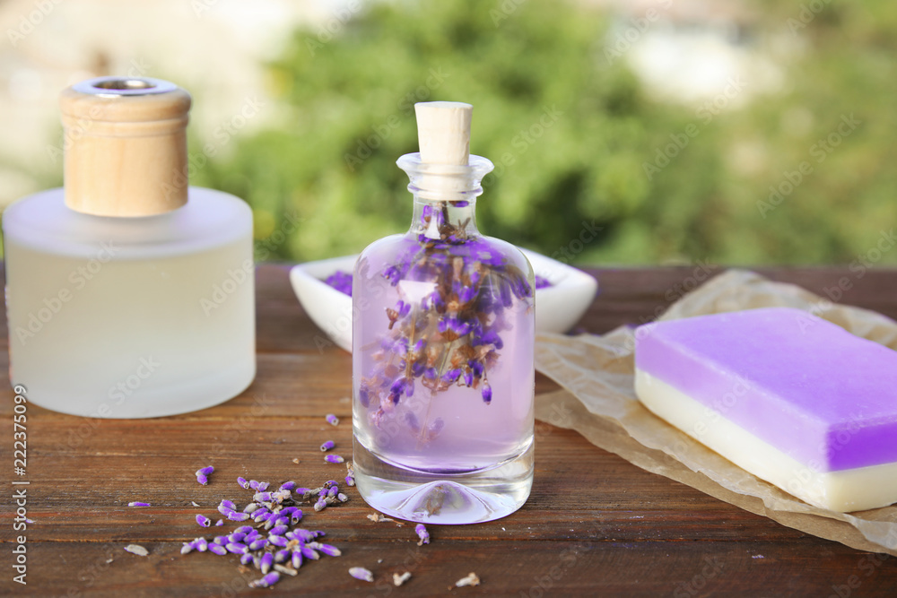 Natural herbal oil and lavender flowers on table against blurred background Natural herbal oil and lavender flowers on table against blurred background