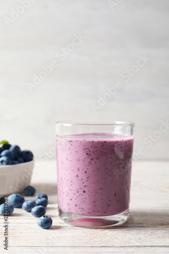 Tasty blueberry smoothie in glass and bowl with fresh berries on table