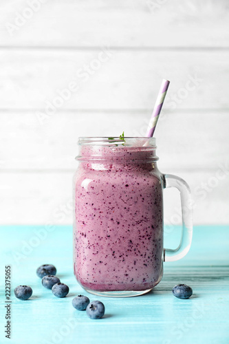 Tasty blueberry smoothie in mason jar and berries on table