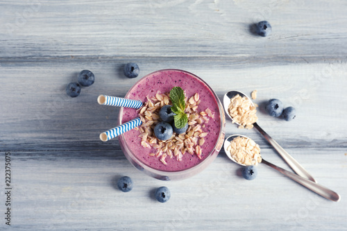 Tasty blueberry smoothie in glass, berries and oatmeal on wooden table, top view