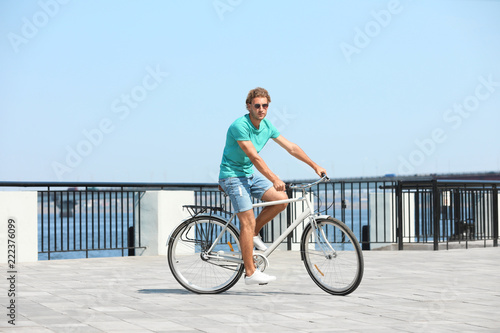 Handsome young man riding bicycle outdoors on sunny day