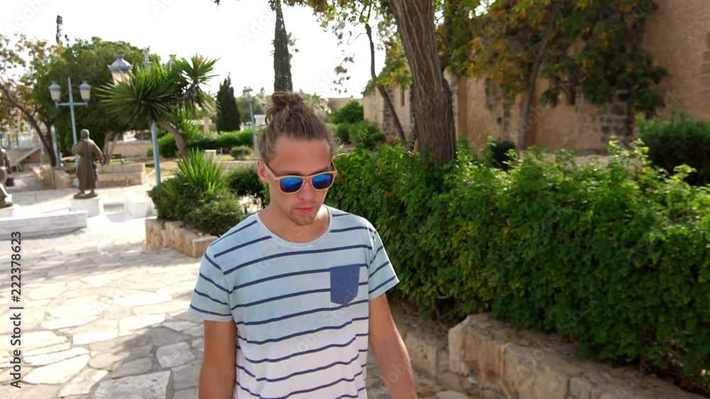 Modern man in sunglasses walking in tropical city. Stylish man in sun glasses enjoy summer walk. Male tourist walking on resort. Hipster man in sunglasses enjoy summer trip Modern man in sunglasses walking in tropical city. Stylish man in sun glasses enjoy summer walk. Male tourist walking on resort. Hipster man in sunglasses enjoy summer trip