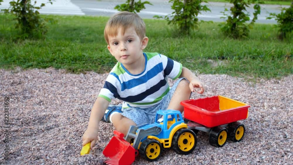 4k video of little toddler boy playing on playground and loading gravel in toy trailer 4k video of little toddler boy playing on playground and loading gravel in toy trailer