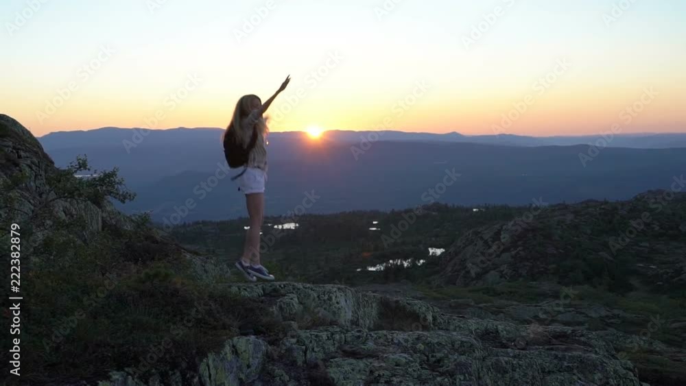 Happy young woman on the sunset high in the mountains with open waving hands. Slow motion Happy young woman on the sunset high in the mountains with open waving hands. Slow motion