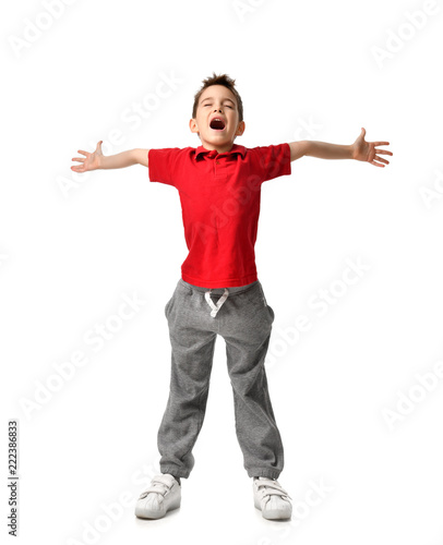 boy kid in red t-shirt and grey pants spread hands up happy smiling screaming laughing isolated on white 