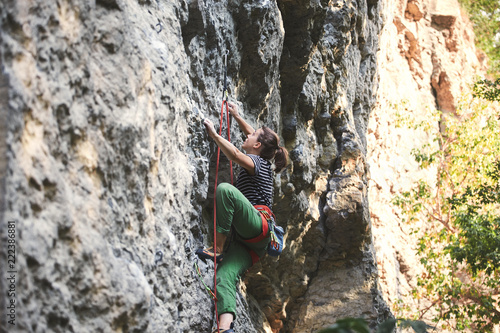 young woman rock climber climbing on the cliff