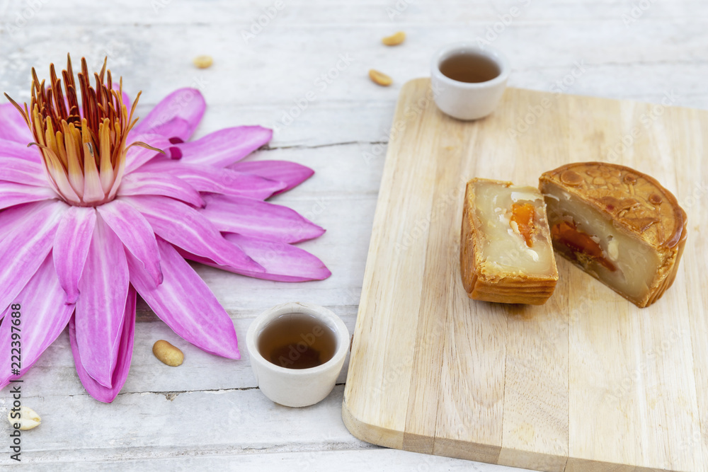 Fototapeta premium Flat lay of Mid Autumn festival Moon cake on old white table with pink water lily
