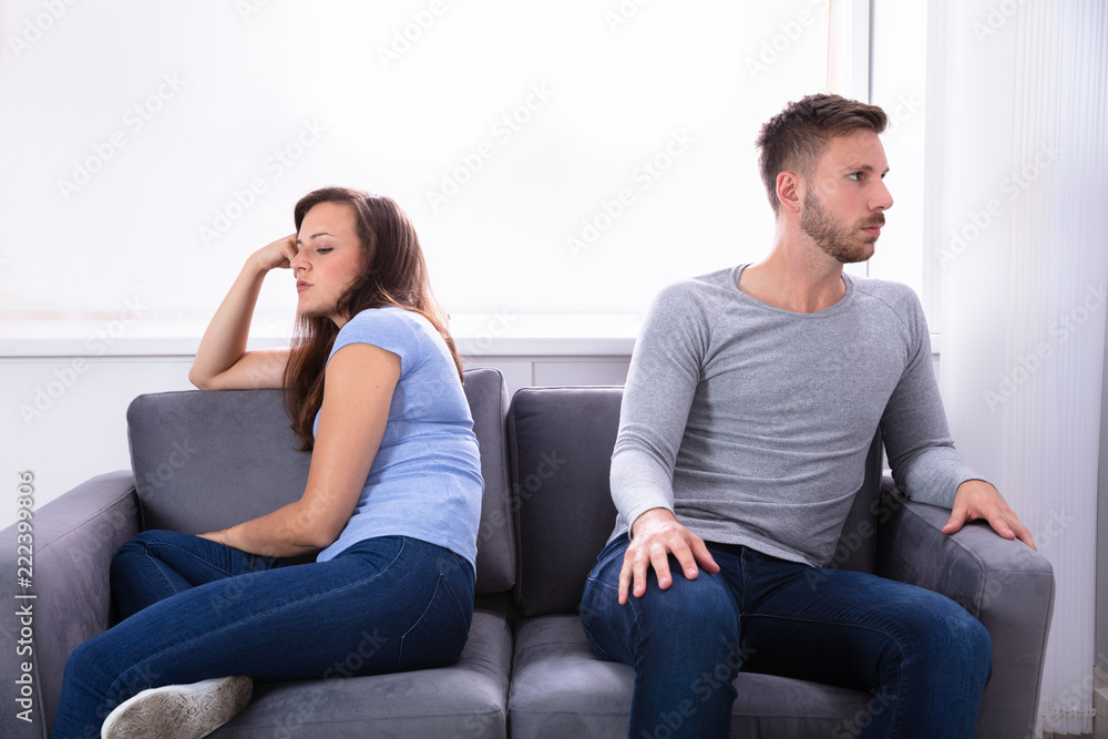 Upset Couple Sitting On Sofa