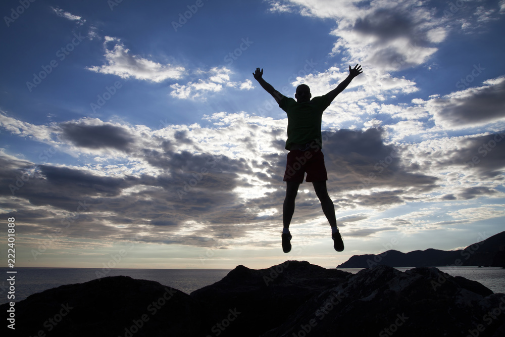 Man jumping on cliffs in sunset