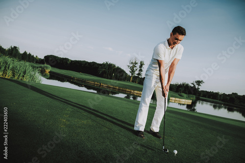 Young Man in White Clothes Playing Golf on Field.
