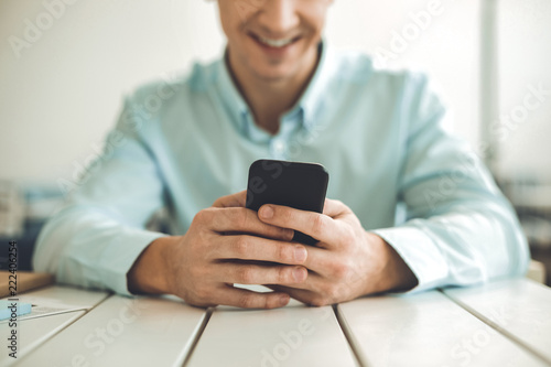 Digital device. Close up of a modern smartphone being held by a joyful young man