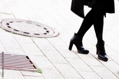 legs of a woman dressed in black standing on sidewalk
