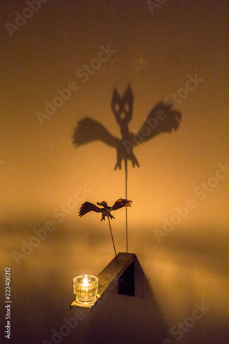 Fabulous shadow of spider bat is reflected on wall from flame of candle. Black Ghost theatre of shadows, Holiday Halloween.
