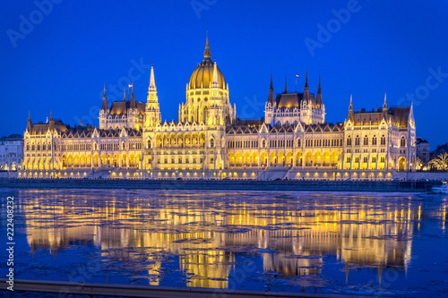 Night view of illuminated Hungarian Parliament Building is seat of National Assembly of Hungary with beautiful reflection during spring on ice drift Danube River, Budapest, Hungary.