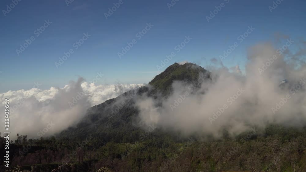 Tops of mountains with running clouds. Landscape slopes of the mountains with the forest in the morning fog and clouds. Banyuwangi Regency of East Java, Indonesia. 4K Tops of mountains with running clouds. Landscape slopes of the mountains with the forest in the morning fog and clouds. Banyuwangi Regency of East Java, Indonesia. 4K